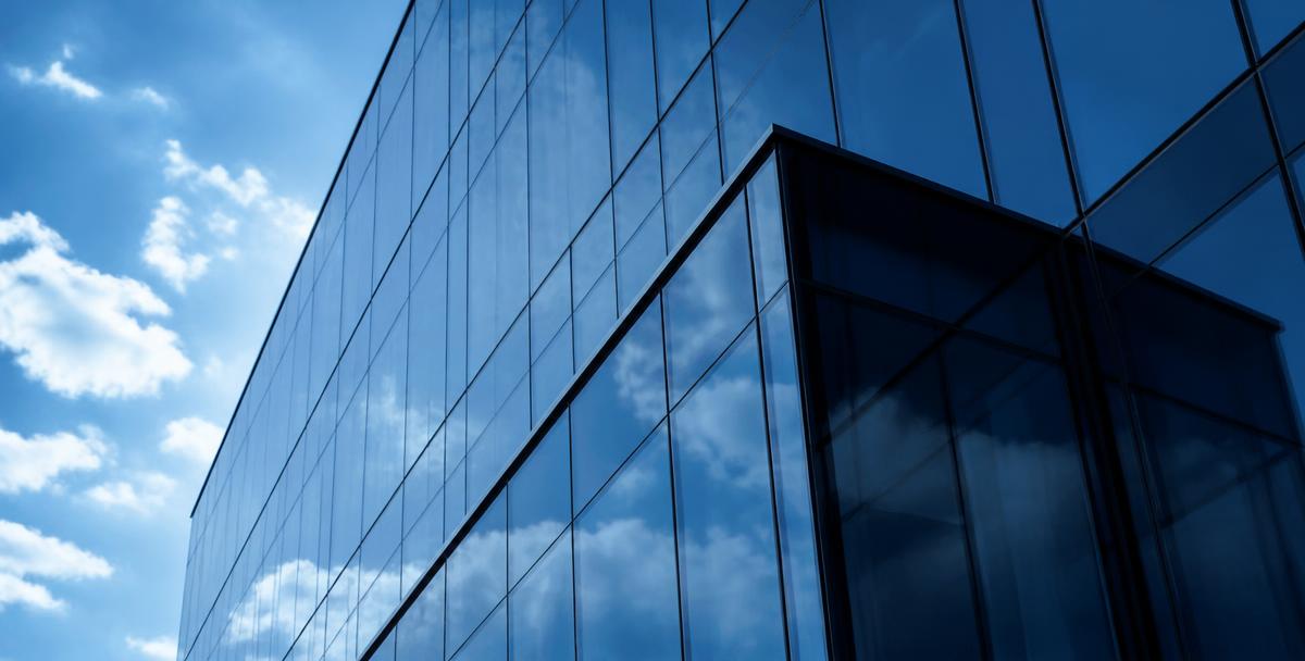 Glass office tower facade reflecting the sky